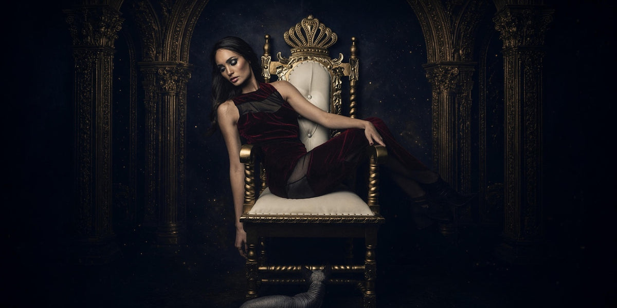 Woman seated on a crown-back throne in a dramatic arched interior