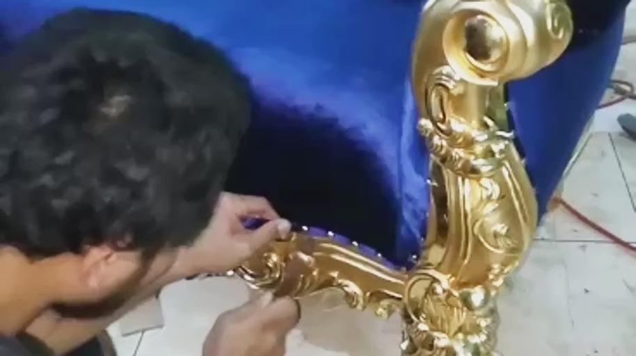 Finishing the Trim — The upholstered edge receives its finishing details beside the gold frame.